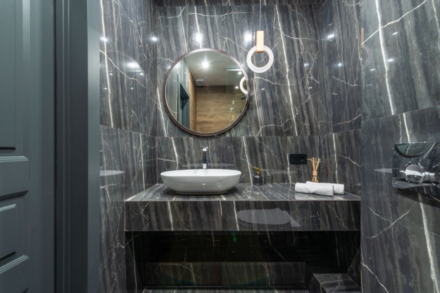 Round bathroom mirror above a marble vanity